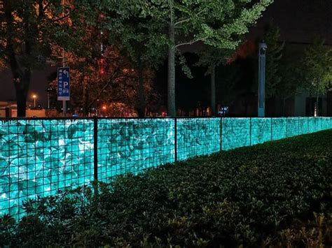 A Fence That Has Some Lights On It In The Night Time With Trees And
