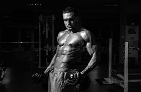 Bodybuilder In Gym Training And Workouts Dumbbells Exercises Sportsman With Naked Torso
