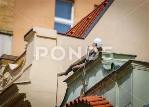 A Sculpture Of A Naked Girl Lying On The Edge Of The Roof Of A Building With Stock Photo