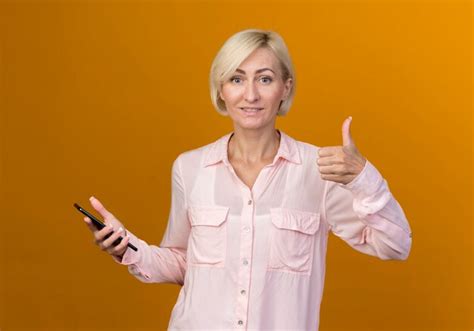 Heureux Jeune Femme Slave Blonde Tenant Le T L Phone Et Son Pouce Vers Le Haut Isol Sur Un Mur