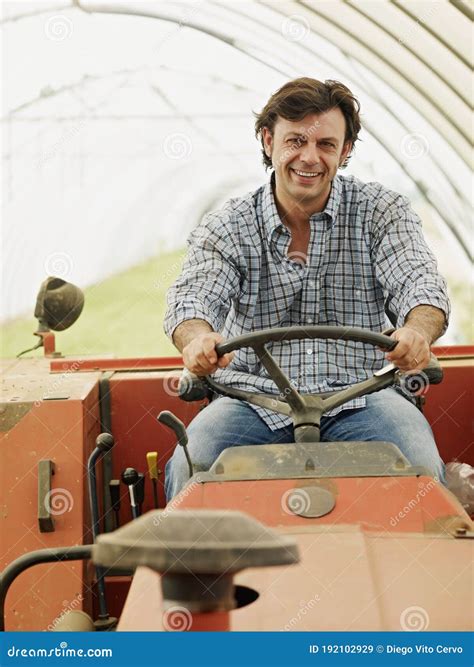 Portrait Of Male Farmer Driving Farm Tractor And Smiling Stock Image