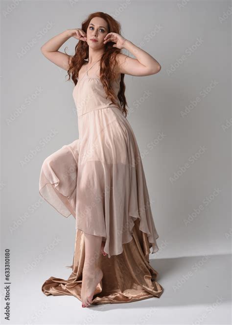 Full Length Portrait Of Beautiful Female Model With Long Brunette Hair Wearing A Creamy Pink
