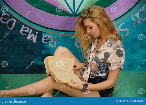 Une Femme Blonde Lit Un Livre Sur Un Divan Image stock Image du curieux pièce
