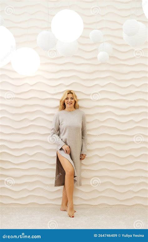 Beautiful Slender Mature Woman Posing Against A Beige Wall With Wavy Lines Woman Smiling And