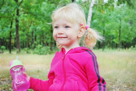 Une Petite Fille Blonde Aux Yeux Bleus Tenant Une Bouteille De L Eau Avec E Photo Stock Image