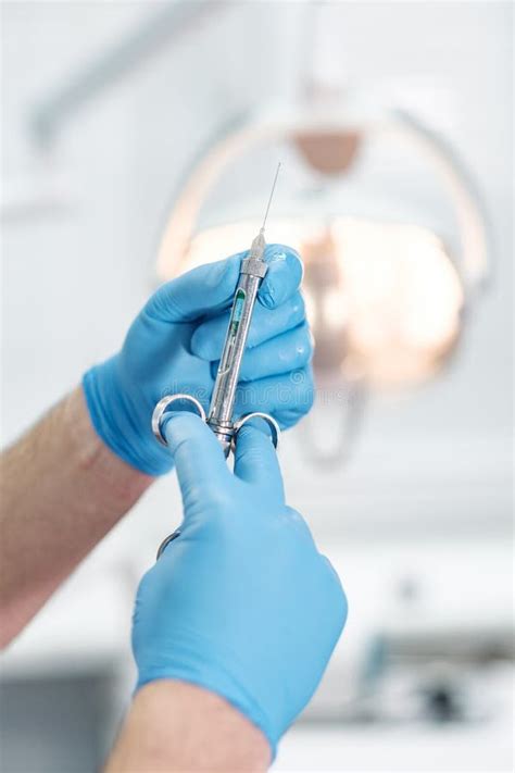 Доктор Anesthetist держит шприц в его руках и смотрит в рамку Стоковое ...