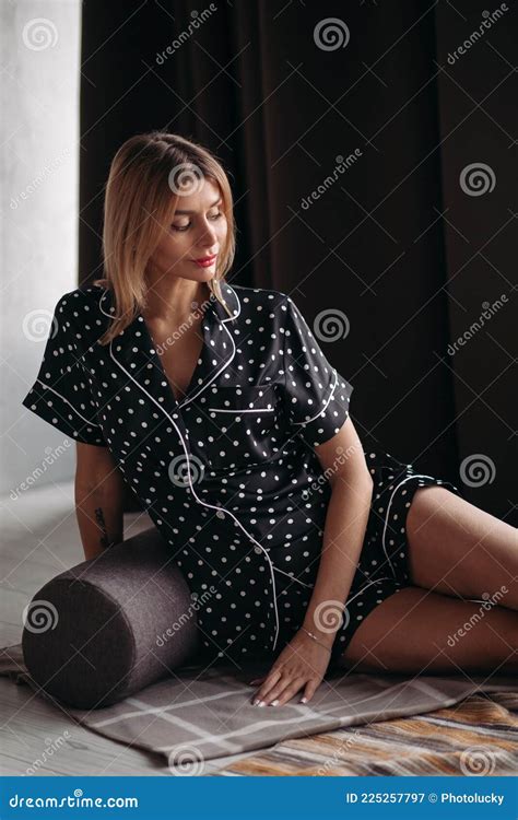Blonde Adult Female With Beautiful Face Sitting On The Coverlet And Posing To The Camera Stock