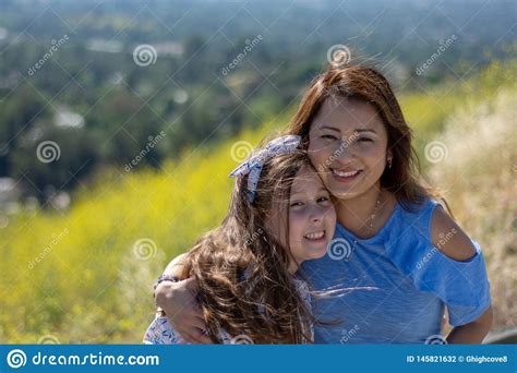 M E E Filha De Latina Que Sorriem E Que Riem Em Um Monte Na Frente Das Flores Amarelas Foto De