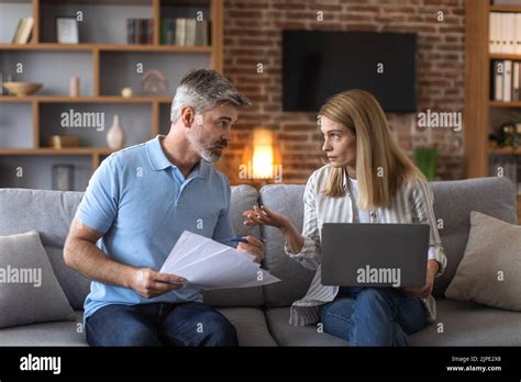 Serious Mature Caucasian Husband And Wife Work With Documents And Laptop Pay Taxes Stock Photo