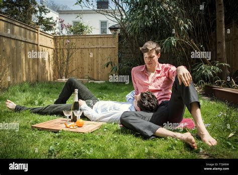 Gay Couple Relaxing On Field In Backyard Stock Photo Alamy