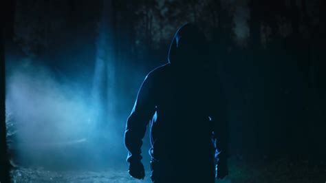 un amenazador masculino figura en un noche y brumoso bosque. un hombre ...