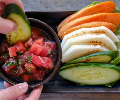 A Person Holding A Small Bowl Filled With Sliced Up Vegetables And