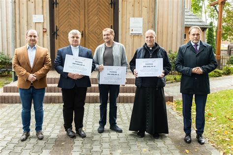 poseł Lorek z prawej wręcza czeki duchownym w celu wyciągnięcia ich