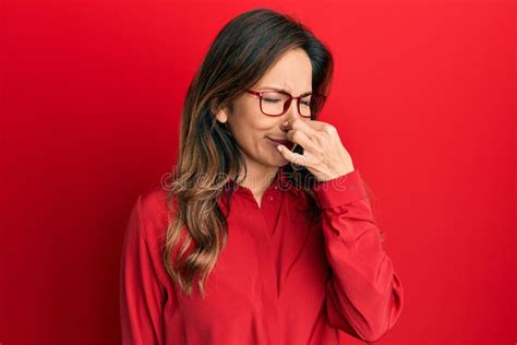 Young Latin Woman Wearing Casual Clothes And Glasses Smelling Something