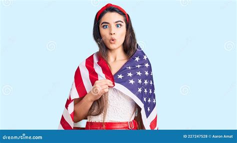 Jovencita Adolescente De Brunette Sosteniendo La Bandera De Estados Unidos Asustada Y Asombrada