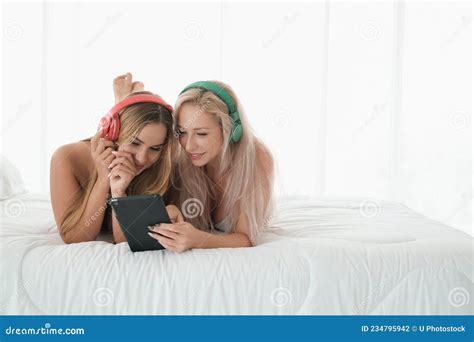 Two Caucasian Girls Wear Bikini On The Bed Playing With Tablet And Headphone Stock Photo Image