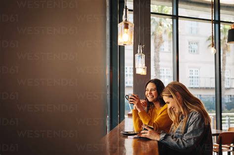 Two Female Friends Laughing And Having Fun At A Cafe Two Women