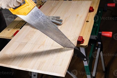 vue latérale du sciage d une planche de bois avec une scie à main