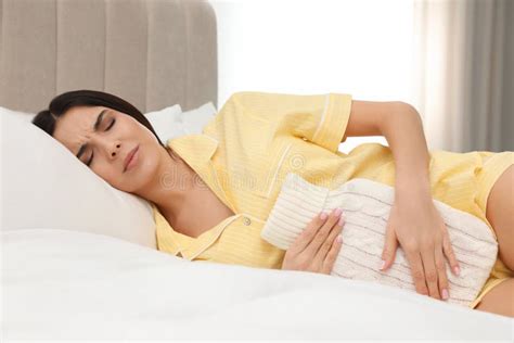 Woman Using Hot Water Bottle To Relieve Menstrual Pain On Bed At Home Stock Photo Image Of