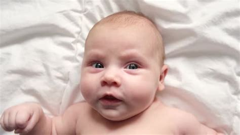 Happy Naked Baby In Diaper Lying On His Back On The White Sheet Stock