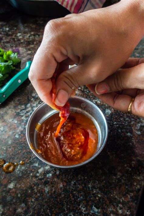 Person Pouring Red Hot Chilli Pepper Sauce In A Bowl In An Indian