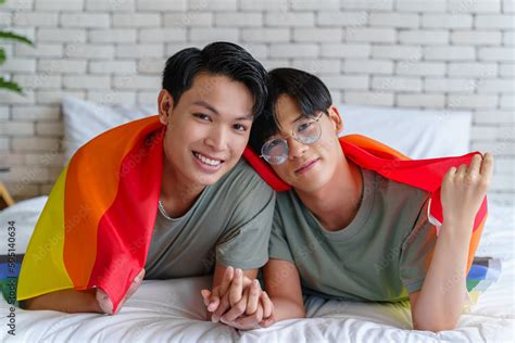 Happy Gay Asian Couple Lying On A Bed And Cover Themselves With Pride Flag Stock Photo Adobe