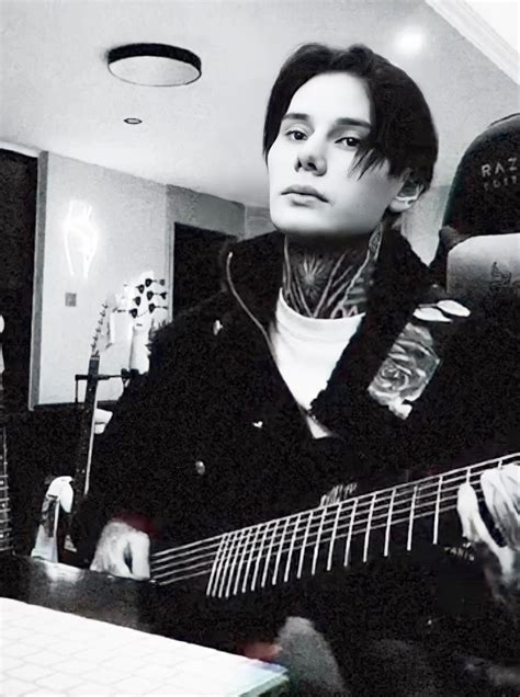a woman with tattoos playing an electric guitar in a room full of other ...