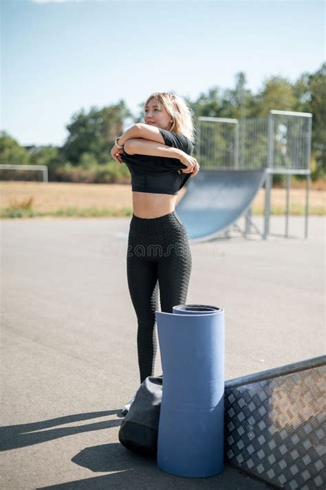 Toned Blonde Woman Taking Off Her Clothes While Preparing For The Workout On Street Stock Image