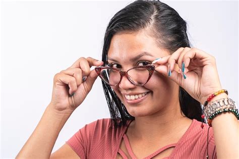 Mujer latina sonriente con gafas mirando a la cámara sobre fondo blanco Foto Premium