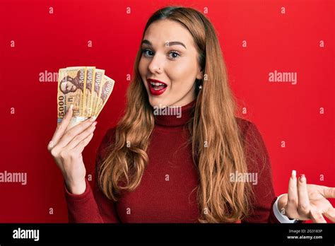 Jeune femme blonde détenant 5000 billets de forint hongrois célébrant la réussite avec un