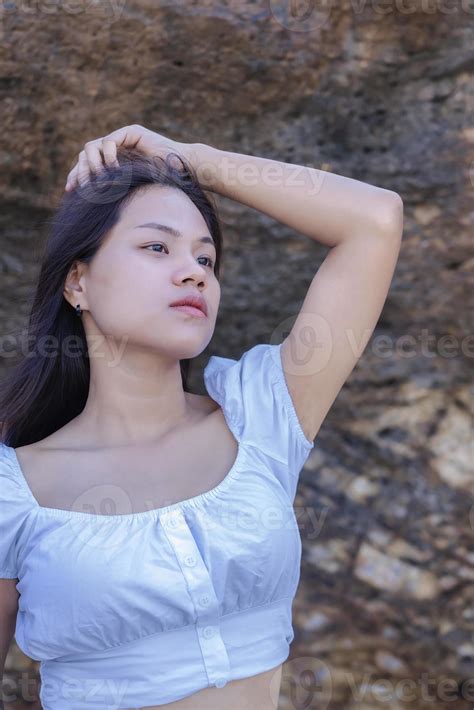 retrato de hermosa mujer de moda en bikini blanco posando en la playa de roca joven asiática