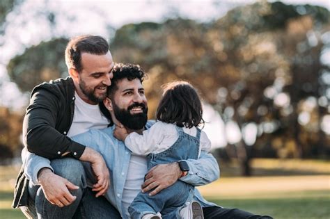 Familia gay masculina abrazándose y feliz en el parque con su pequeña hija Foto Premium