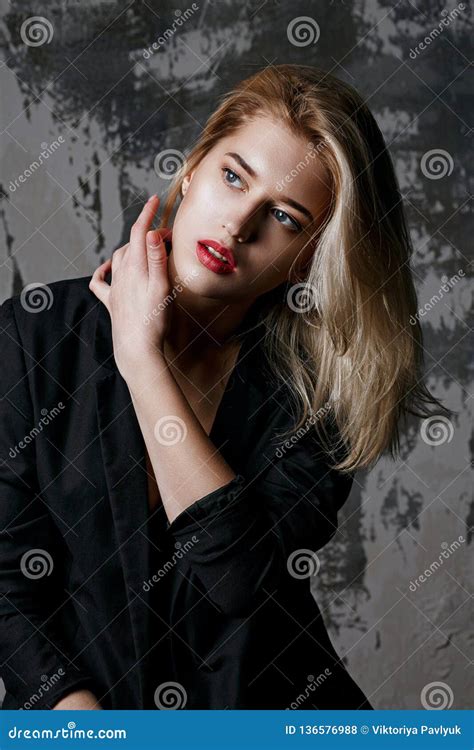 Portrait Of Glamorous Blonde Model Wearing Black Jacket Posing At Studio With Shadows On Her