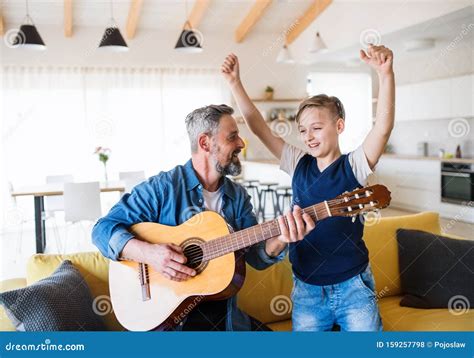 Mature Father With Small Son Sitting On Sofa Indoors Playing Guitar Stock Photo Image Of