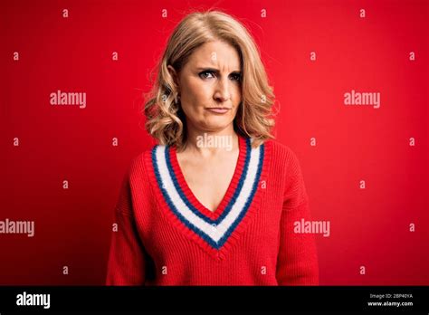 Middle Age Beautiful Blonde Woman Wearing Casual Sweater Over Isolated Red Background Skeptic