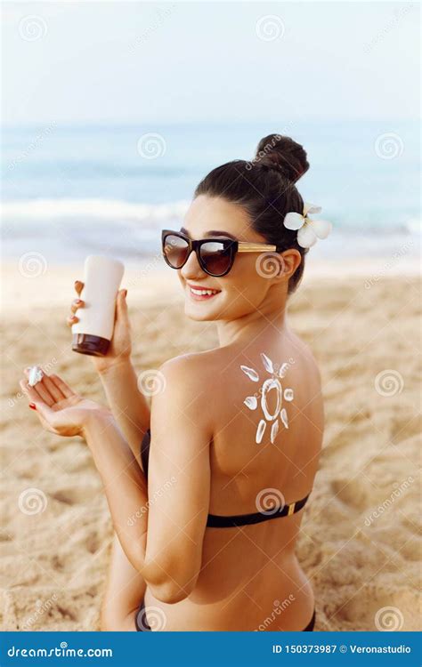 Woman Applying Sun Cream On Tanned Shoulder In Form Of The Sun Sun