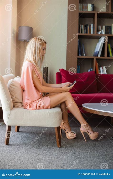 La Belle Blonde Mince De Fille Dans Une Robe Rose à La Mode D été Dans Des Talons Hauts S assied