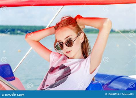 Jeune Fille Blonde En Lunettes De Soleil Portrait Sous Un Auvent Rouge Sur Fond De Lac Photo