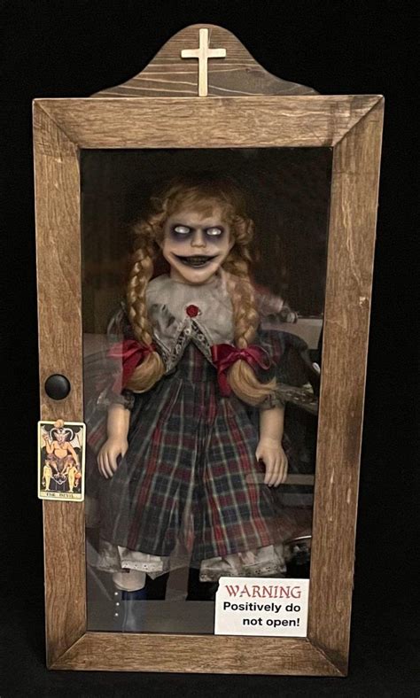 A Creepy Doll In A Wooden Frame With A Cross On The Top And An Image Of A