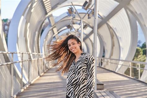Retrato de una joven latina con el pelo volando mientras mira a la cámara mostrando sus dientes