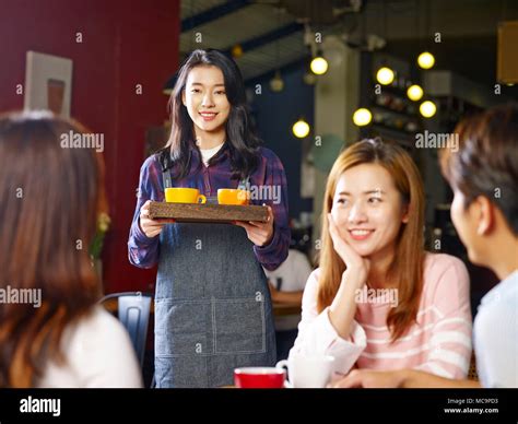 young smiling asian waitress serving customers  coffee shop focus