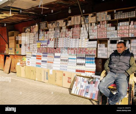 A Street Vendor Posing In Front Of His Cigarette Stall At The Green