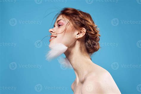 Pretty Woman Naked Shoulders And Fluffy Earrings Bright Makeup Blue Background Stock
