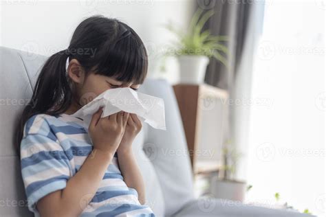 Unhealthy kid blowing nose into tissue, Child suffering from running