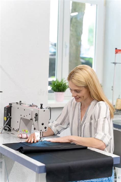 Blonde Cute Female Designer Sitting Sewing Machine Looking Involved