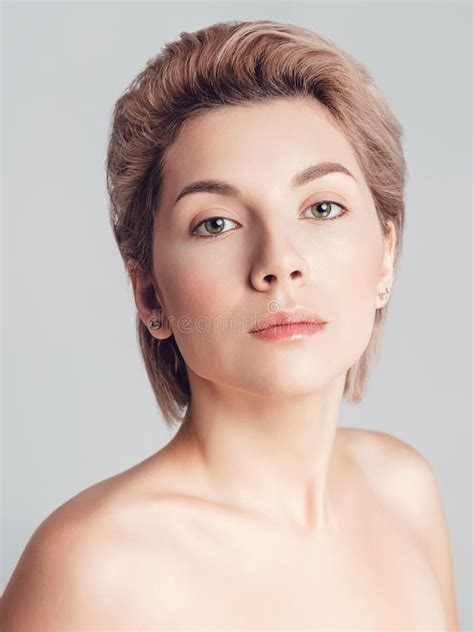 Portrait Of A Beautiful Blonde With Short Hair And Green Eyes On A Gray Background Makeup Nude