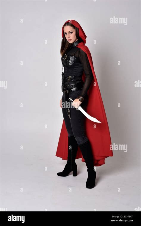 Portrait Of Brunette Girl Wearing Black Leather Catsuit Red Cape Full Length Standing Pose