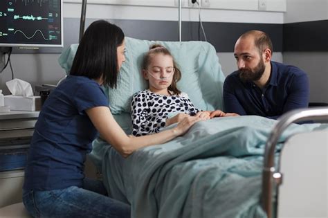 Pai E Mãe Podem Acompanhar Filho No Hospital - Pais preocupados sentados ao lado da filha doente hospitalizada em ...