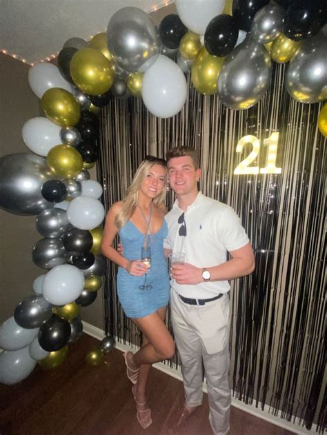 a man and woman standing in front of balloons with the number twenty
