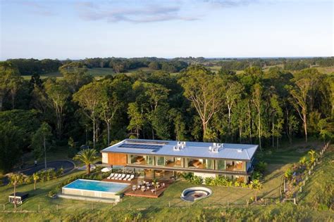 An Aerial View Of A House In The Middle Of A Lush Green Field And Trees